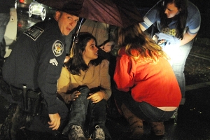 Town of Elon police help shield Elon University sophomore Alex Trice from the rain after a car struck her crossing Williamson Avenue.